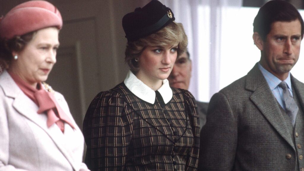 Princess Diana wears a tartan dress with a white collar and stands between Queen Elizabeth II, who wears a light pink coat, and King Charles
