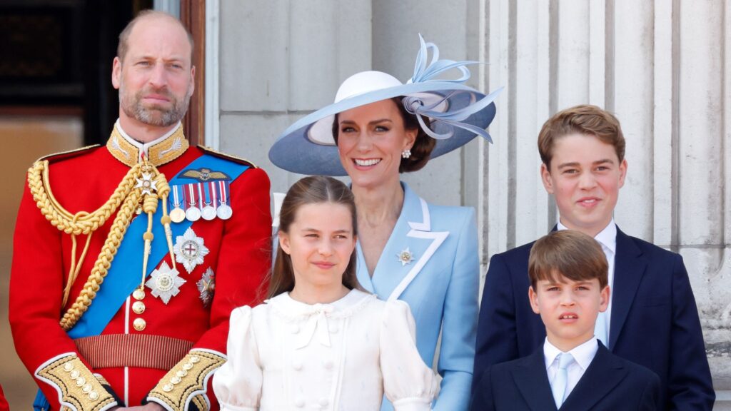 Prince William Struggles to Stop His Children Doing One Thing Prince William wears red military uniform and has a bald head and a beard, and stands next to wife Princess Middleton who wears a baby blue coat dress and matching hat, and their three kids
